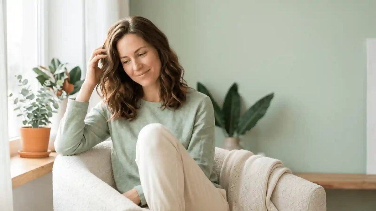 Calm woman gently checking her hair, illustrating stress and hair loss and drug-free ways to support healthier-looking hair